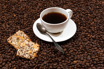 White coffee mug and cookies on the coffee beans background