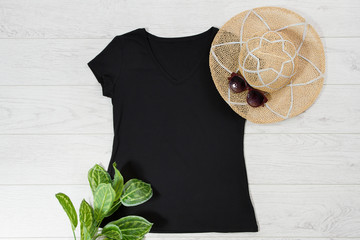 T shirt black. T-shirt Mockup flat lay with summer accessories. Hat and sunglasses on wooden floor...