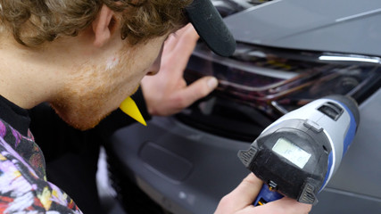 Close up of paint protection film installation on front bumper of modern luxury car. PPF is...