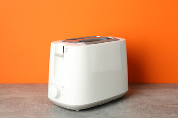 Toaster on grey table against orange background, space for text