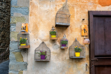 Vintage decoration on a stone wall with flowers in empty bird cage in the old provincial Tuscany...