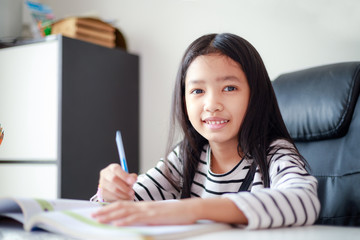 Smile little Asian girl doing homework with happiness for self learning and education concept select focus shallow depth of field