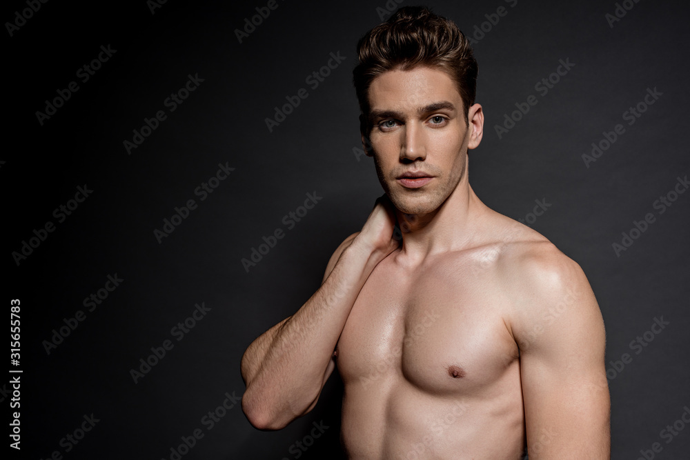 Wall mural sexy young naked man with muscular torso posing on black background