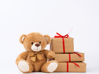 cute beige teddy bear and stack of gifts in boxes wrapped in brown eco paper