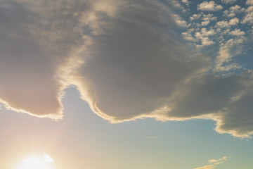 Beautiful cirrus and cumulus clouds on a bright blue sky lit by the sun. Sunset and dusk. Colorful positive natural landscape