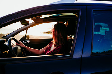 young woman driving a car at sunset. travel concept