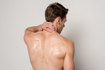 back view of man having neck pain isolated on grey - obrazy, fototapety, plakaty