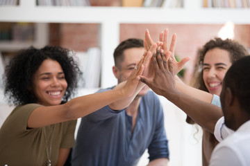 Motivated diverse people give high five for shared success