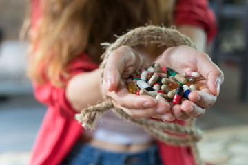 Close up of tied rope on woman hand while holding capsule of drugs. Drug addiction concept