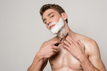 sexy man with muscular torso shaving with straight razor isolated on grey - obrazy, fototapety, plakaty