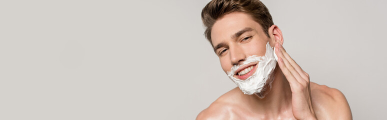 smiling sexy man with muscular torso applying shaving foam isolated on grey, panoramic shot