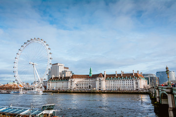 View on the London Eye and Houses of Parliament on the Thames river bank, London.