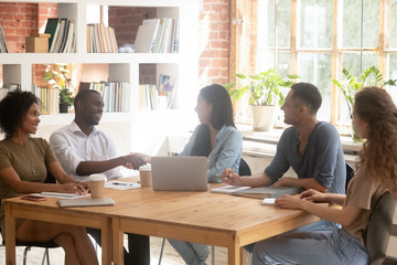 Multiracial millennial people handshake getting acquainted at meeting