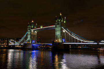 Illuminated London Tower bridge at night over the dark Thames water, United Kingdom