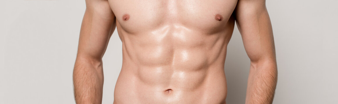 cropped view of sexy man with muscular torso isolated on grey, panoramic shot