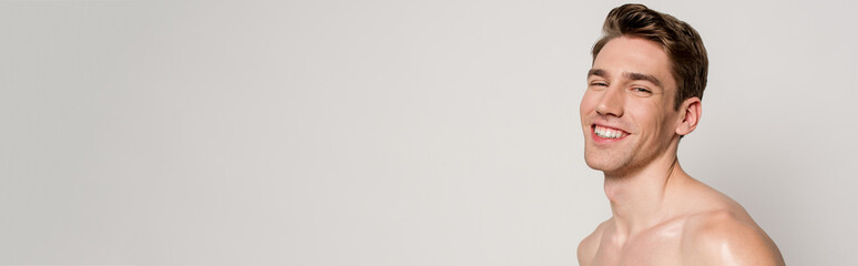 smiling sexy man with muscular torso isolated on grey, panoramic shot