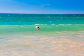 Fototapeta na wymiar Swimming person in turquoise waters at Algharve coast in Portugal in summer