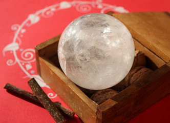 Crystal quartz ball in wooden box on red background