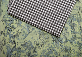 Top view of checkered kitchen tablecloth on concrete background.