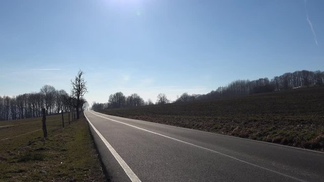 A footage of an empty road lined by trees and nature.