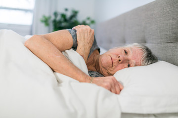 A Senior woman having sleep disorder, lying in bed