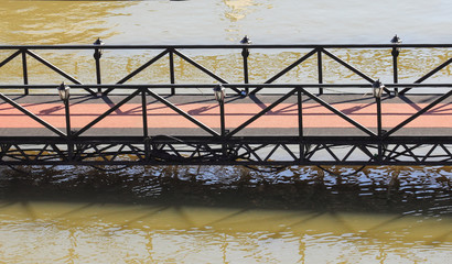 Metal bridge crossing above gray river.