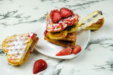 Waffle hearts with fresh strawberries and jam on a white marble table