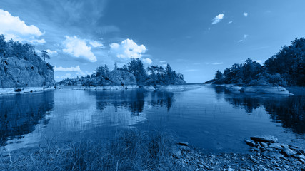 The chic view of the rocky islands on the lake is toned in a trendy classic blue color. The Island Honkasalo