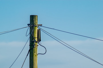 Telegraph pole with cables connected to it and set against a contrasting  beautiful blue sky.