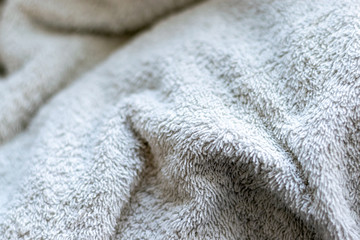 White fluffy cotton bathroom towel showing a close up of the large fibres of the towel with the rest of it blurred in the background for added depth.