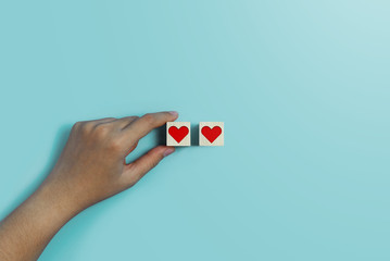 Valentine's day concept. Hand holding wooden cube on blue background.