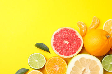 Citrus fruits and leaves on yellow background, top view
