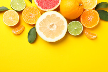 Fototapeta na wymiar Citrus fruits and leaves on yellow background, top view