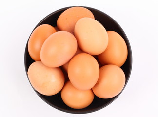 brown eggs in black bowl on white background 