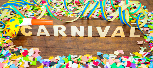 Carnival background - colorful confetties, balloons streamers and blowouts on rustic wooden table