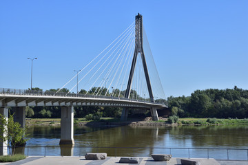 Fototapeta na wymiar Wiszący most nad rzeką na bezchmurnym niebie w gorący, letni dzień.
