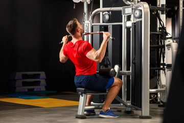 Young muscular man pulling up on horizontal bar in a gym