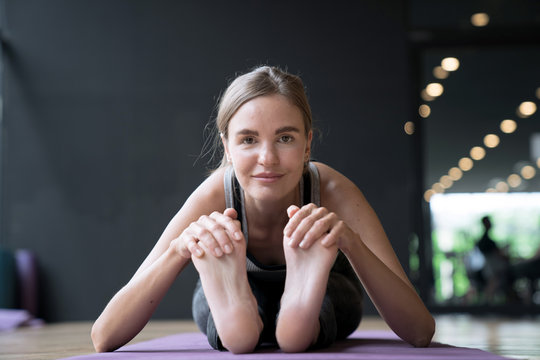 Young woman practicing yoga, sitting in Seated forward bend exercise.