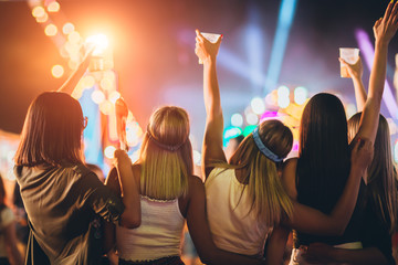 Back view of group of girls having fun at the music festival - obrazy, fototapety, plakaty