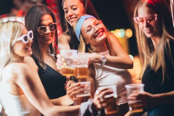 Female friends toasting with beer at the music festival