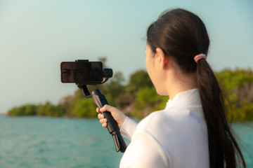 Blogger Asian woman record vlog video and sharing content on streaming platform with Social Network. female enjoy in front of camera using mobile phone make vlogging live feeds on social media network