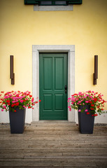 Fototapeta na wymiar Wooden house front door with large flower pots