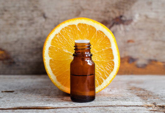 Small bottle with sweet orange essential oil (extract, tincture, infusion, perfume). Aromatherapy, spa and herbal medicine ingredients. Old wooden background. Copy space
