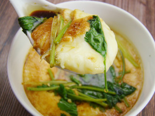 Steamed egg in white bowl, white spoon filled with egg and parsley on top