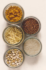 Fototapeta na wymiar Various raw cereals, grains, beans and pasta for cooking healthy food in glass jars on a wooden table, light background flat, Clean food, vegan, balanced diet,zero waste,eco friendly,plastic free