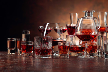 Set of strong alcoholic beverages in glasses on a brown background.