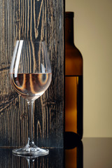 Bottle and glass of white wine on a black table.