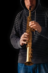 soprano saxophone in the hands of a guy on a black background