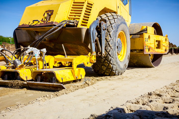 Plate compactor is mounted on road roller to compact soil at construction site