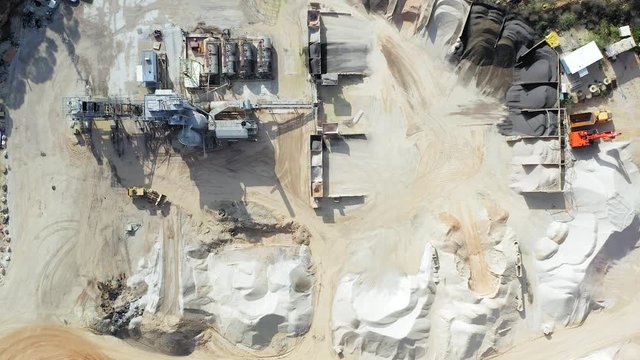Aerial view of a large Quarry during work hours with Stone sorting conveyor belts and an open pit mine.
